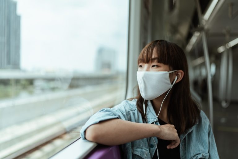 woman wearing face mask looking out window
